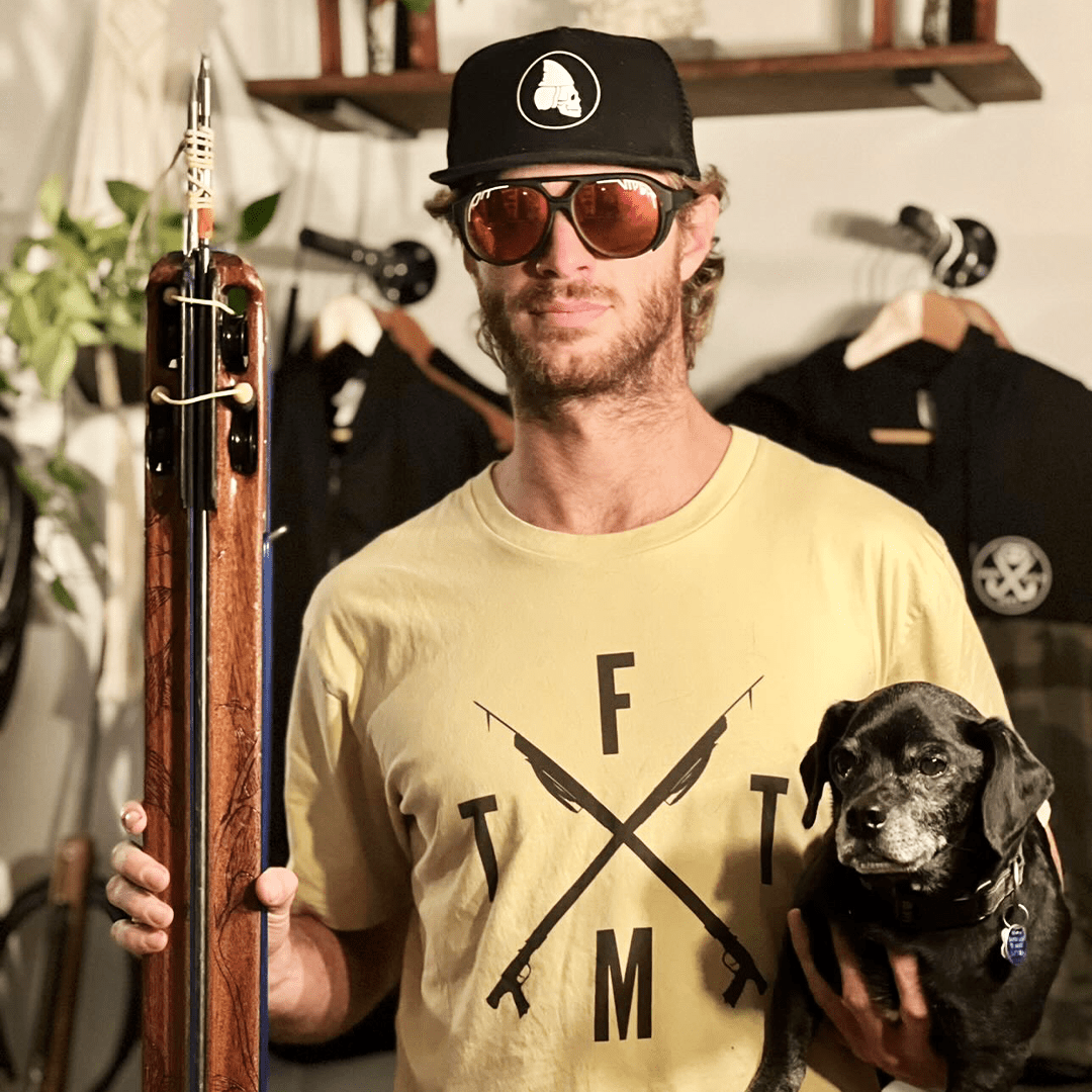 Spear fisherman holding speargun wearing spearfishing shirt and hat