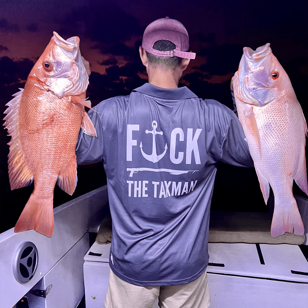 Fisherman holding two large fishing. Fisherman is wearing a grey fishing jersey